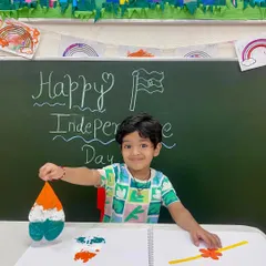 A proud smile and a beautiful creation. This student shows off his leaf-printed artwork, a perfect example of how we blend learning about national holidays with fun, creative expression.