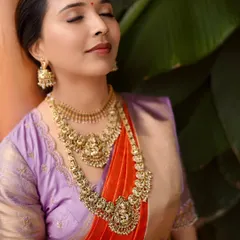 A close-up of our client Anusha, serene and beautiful on her engagement day. The rich temple jewelry perfectly complements the intricate zari work on her lavender and red silk saree.