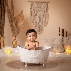 It's time for a morning bath! A happy baby enjoys a splash in a classic clawfoot tub in our cozy boho setup.