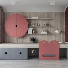 A playful and modern study table design for a child's room. The unit features unique circular and arched cabinet doors in pink and grey, open shelving, and a long desk surface.
