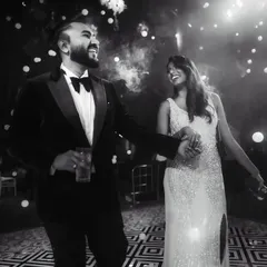 A classic black and white shot from the reception. The couple shares a dance and a laugh, surrounded by a beautiful bokeh of lights, creating a timeless and joyful memory.