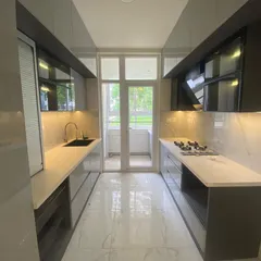 This is the other side of the galley kitchen, showing the seamless integration of appliances and storage. The glossy, dual-tone cabinets and marble-patterned backsplash create a sophisticated look.