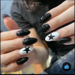 A striking monochrome design. These oval-shaped nails feature a mix of glossy black and white accent nails with a bold black star.