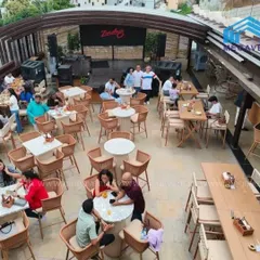 An aerial view of a rooftop restaurant setup, showcasing our durable and stylish cafe chairs and tables. Our retractable roof ensures business can continue, rain or shine.
