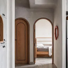 Arched doorways and softened edges are key to my Japandi-inspired designs. This view from the hallway into the bedroom of the 'Unmei' project shows how these elements create a gentle, flowing transition between spaces, enhancing the home's serene feel.