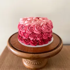 A beautiful cake featuring pink ombre buttercream rosettes. This design is perfect for birthdays and anniversaries, with a little heart plaque that reads "Happy 50th young lady!"