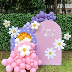 A sweet daisy-themed setup for Ariana's first birthday. This outdoor decor features a custom pink arch backdrop, a smaller arch filled with balloons, and cheerful daisy cutouts for a fresh, playful feel.