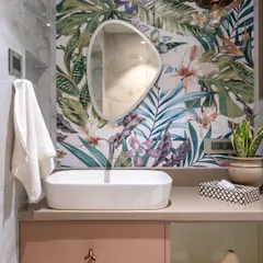 A beautiful blend of nature and modern design. This bathroom features a vibrant tropical leaf wallpaper, which serves as a stunning backdrop for the simple, elegant vessel sink and organic-shaped mirror.