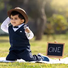 A stylish outdoor portrait of a little boy tipping his hat, holding a vintage-style pocket watch prop for a timeless look.
