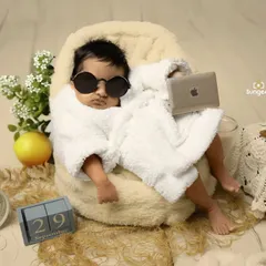This little boss is already taking meetings. A fun and humorous newborn setup featuring a tiny bathrobe, sunglasses, and a laptop, proving that even the tiniest clients can have a big personality.