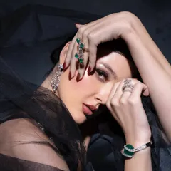 A moody, artistic shot where the model's pose frames the stunning emerald and diamond jewellery. The black veil adds a touch of mystery and contrast.