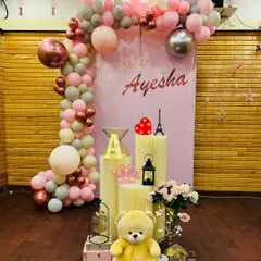 A full view of the Paris-inspired chic birthday decoration. The arrangement includes a personalized backdrop, a balloon arch, and carefully placed props on pedestals to create a sophisticated look.
