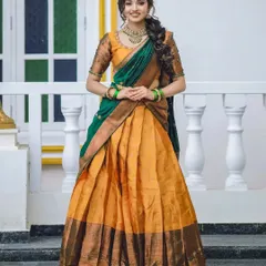 This vibrant yellow and green half-saree is perfectly complemented by an antique kempu and green stone choker set. This is a wonderful, youthful look for an engagement or pre-wedding puja.