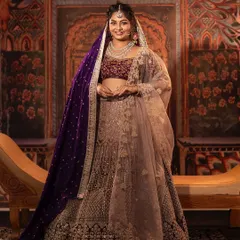 This grand lehenga in shades of purple and mauve is perfect for a reception or sangeet. The velvet blouse is heavily embroidered, and the double dupatta, one in sheer net and another in rich velvet, adds a layer of elegance.
