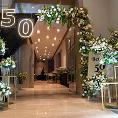 For a glamorous 50th birthday, I designed this grand entrance to set a tone of sophistication and excitement. The combination of lush white florals, dramatic black draping, and modern neon lighting created a truly fabulous welcome for the guest of honor and her friends.