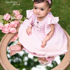 A moment of reflection. This creative outdoor shot uses a mirror to capture a unique and artistic portrait of a baby girl amidst the greenery.