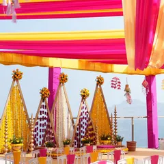 We bring vibrancy to tradition with setups like this stunning outdoor Haldi ceremony. The brilliant pink and yellow drapes create a joyful canopy, while the intricate marigold backdrops and floral arrangements set the stage for a day filled with laughter and blessings.