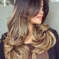 This is the popular butterfly haircut paired with a beautiful blonde balayage. The long, sweeping layers create movement and volume, while the expertly blended color gives a sun-kissed, natural-looking finish. This style is great for adding body to long hair.