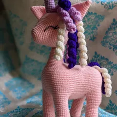 A magical pink unicorn with a colorful, curly mane and tail. The colors can be customized to your preference.
