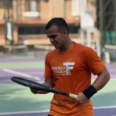 A moment of focus between points. A player wearing our French Touch India shirt inspects his racquet, showing the mental preparation and attention to detail we encourage.