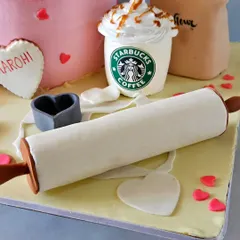 A detail shot from the baker-themed cake, showing the edible rolling pin, a bag of "flour," and a miniature Starbucks Frappuccino, complete with caramel drizzle.