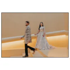 An artistic shot capturing the couple's entrance. The motion blur on the groom adds a dynamic, fleeting quality, while the bride remains in sharp focus, symbolizing a moment of calm elegance amidst the whirlwind of the celebration.