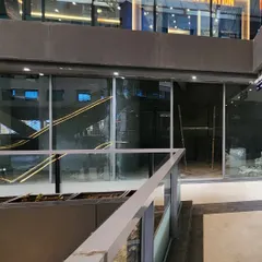 The storefront is the first point of contact with the customer. This image shows the installation of the large glass facade, designed to create a modern, transparent shell that invites curiosity about the intricate world being built inside.