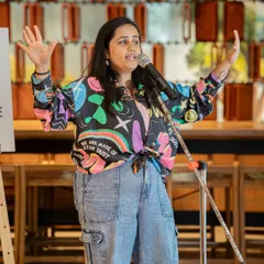 A performer with arms outstretched, sharing her truth during our "Love Without Labels" meetup. The theme celebrated being seen, held, and loved in all your colors.