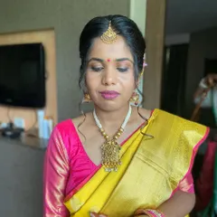 A beautiful South Indian bride in a vibrant yellow and pink silk saree. The makeup features defined eyes and a bold pink lip to match her blouse.