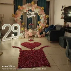 I can turn a large living room into the perfect party space. This 29th birthday setup includes a full circular balloon arch, a neon sign, light-up numbers, and a rose petal path, creating a memorable photo point for the celebration.