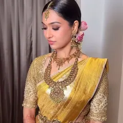 A radiant bride in a golden-yellow Kanchipuram silk saree. I designed her blouse with heavy, all-over embroidery to create a look of pure opulence for her wedding day.