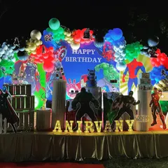 An action-packed Avengers theme party for a 7th birthday, perfect for a young superhero fan. The setup includes a large backdrop with all the main characters, life-sized cutouts of Thor, Hulk, and Iron Man, and a multi-colored balloon arch.
