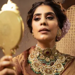 A close-up shot focusing on the magnificent bridal jewelry. The image highlights the craftsmanship of the multi-layered necklace and the model's traditional makeup, perfect for a high-end jewelry campaign.