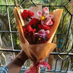A beautiful combination of deep red roses and delicate crochet orchids. This bouquet has a rustic feel with the brown paper wrapping and heart-patterned ribbon.