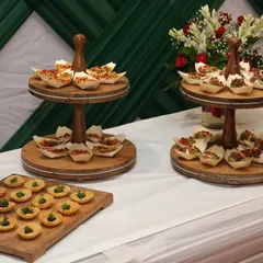 An elegant corporate event setup featuring tiered stands with savory canapés. The clean white and green theme creates a professional yet welcoming atmosphere.