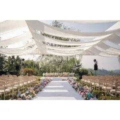 A wide view of a serene garden ceremony setup. We used flowing white drapes to create a soft canopy overhead, with a colorful floral aisle leading to an elegant mandap under a tree.