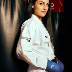 Ready for anything. A student stands prepared in her karate gi and gloves, showing the focus required for sparring. My classes prepare you for many things in life, not just for the dojo.