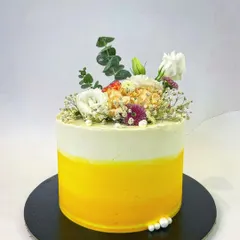 A simple yet stunning design perfect for a summer event. This single-tier cake has a beautiful yellow ombre buttercream finish, topped with a fresh and airy arrangement of white flowers and eucalyptus.