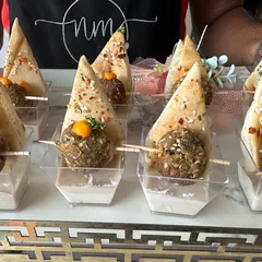 Our Lebanese station offers delicious bites like these Falafel Pita appetizers. Crispy falafel balls are served with creamy hummus and fresh pita bread in individual portions, making them an easy-to-eat and popular party snack.
