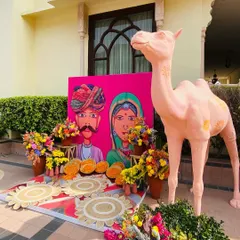 A fun and colorful Mehendi photo booth with a Rajasthani theme, complete with a camel prop.