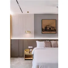 Details matter in creating a sense of luxury. This close-up of the hotel bedroom shows the interplay of textures, from the vertically ribbed wall panels to the soft upholstery and the warm glow of the integrated bedside lighting.