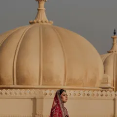 A bride poses against the iconic domes of The Oberoi Udaivilas in Udaipur, her portrait framed by timeless architecture.