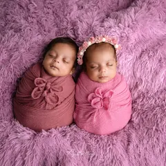 Shades of pink and mauve for these twin girls. Swaddled in coordinating colors with floral accents, they look absolutely precious on a soft purple fur blanket.
