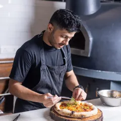 Adding the final touches to a freshly baked pizza right out of the wood-fired oven. It's these small details and the passion behind them that define the food at Camillo's.