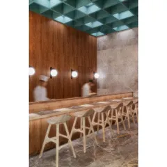The sushi bar at CHAMPON, offering a direct view of the chefs at work. The design here is clean and functional, with a coffered ceiling and simple wood counter that honor the precision of Japanese culinary arts.