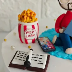 A closer look at the tiny, edible accessories on Ayush's cake, including a bucket of popcorn, a smartphone, and a book. It's these details that tell a story.
