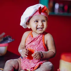Dressed as a little chef, this baby girl is all smiles and covered in flour, ready to "bake" her own cake.
