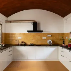The open kitchen features a beautiful vaulted ceiling and a backsplash of handmade yellow tiles, combining modern functionality with warm, natural textures.