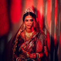 A dramatic portrait of the Bengali bride in her traditional attire. The red lighting creates a powerful and artistic image, highlighting her beauty.