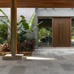 The entrance of the K Residence, where a glass facade offers a glimpse of a luxury car, reflecting the client's passions. The design thoughtfully integrates personal elements into the architectural narrative.